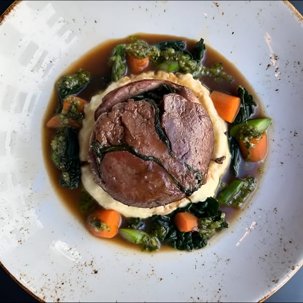 Broma Restaurant's braised short rib with mashed potatoes, carrots, and green vegetables in a rich sauce.