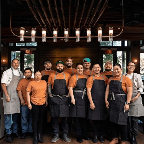 Broma Restaurant staff, a diverse group of 12 smiling chefs and servers, stands together.