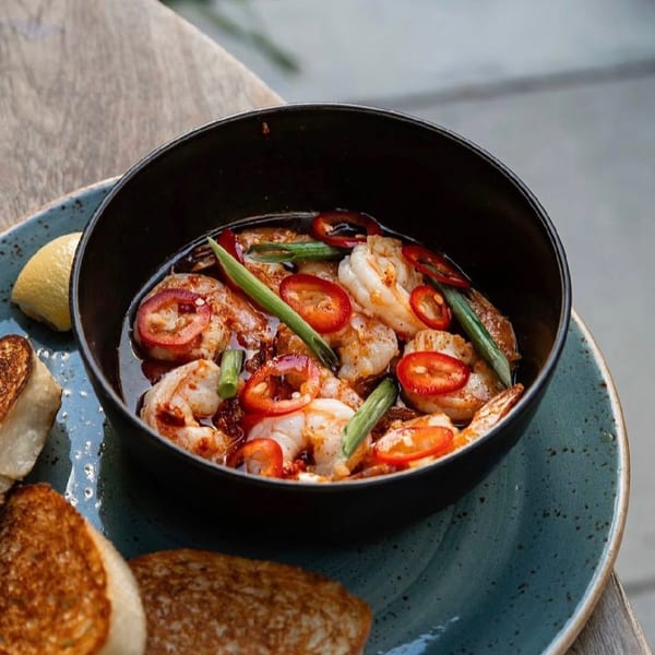 Broma Restaurant's shrimp dish with red peppers and green onions, served with toasted bread and lemon.